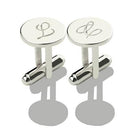 Silver cufflinks with engraved initials 'L' and cursive 'L' displayed on a reflective grey surface.