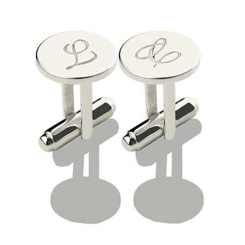 Silver cufflinks with engraved initials 'L' and cursive 'L' displayed on a reflective grey surface.