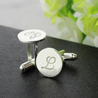 Silver cufflinks with monogrammed initials 'L' on a black textured surface.