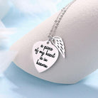 A silver necklace with a heart-shaped pendant engraved with "a piece of my heart is in heaven" and an angel wing charm, displayed on a light blue background.