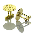 Gold monogram cufflinks with 'ABC' initials, displayed on a reflective surface.