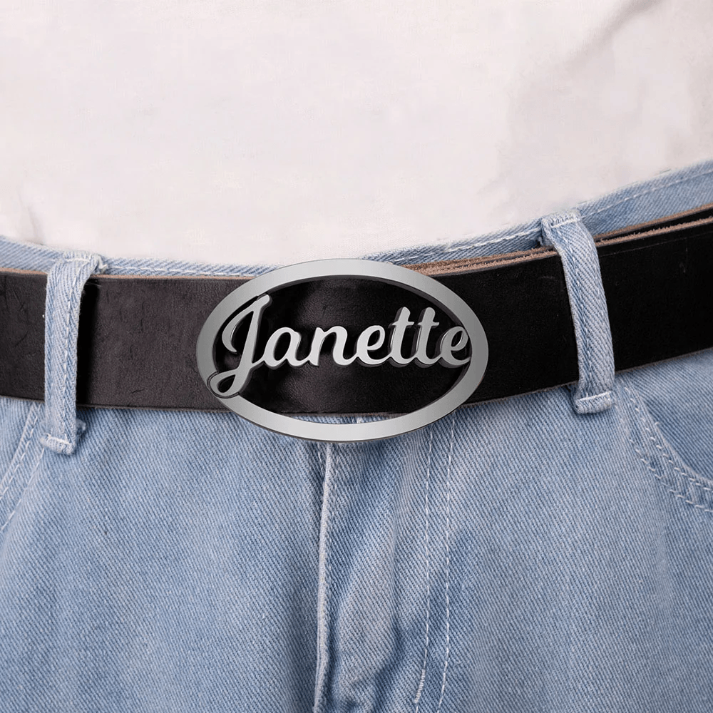 Wearer in blue jeans and a black belt with a silver oval buckle inscribed with 'Janette' in cursive script against a white top.