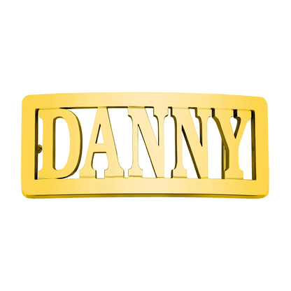 Rectangular gold belt buckle with 'DANNY' in bold uppercase letters, cut through the metal, isolated on a white background.