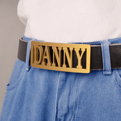 Person wearing a white shirt and blue jeans with a black belt featuring a gold buckle that reads 'DANNY'.