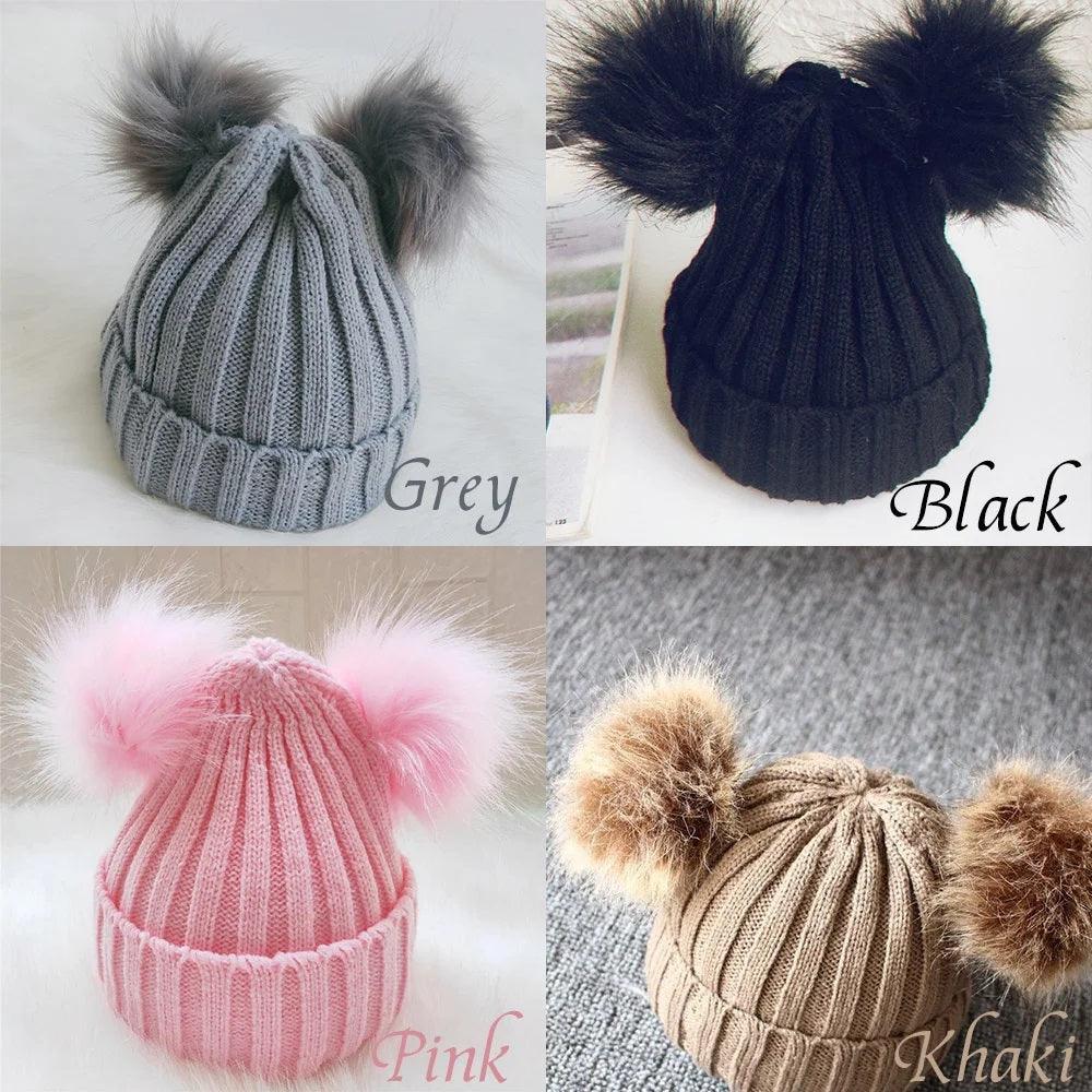 A collage of four knitted baby hats in grey, black, pink, and khaki, each with two contrasting fluffy pom poms on top, labeled with their respective colors.