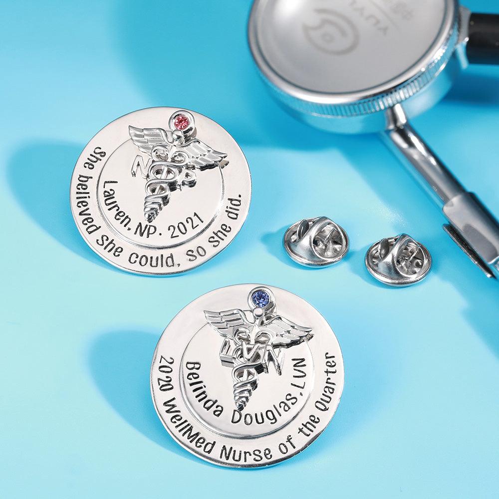 Custom nursing pins with colored gems and motivational quotes, next to a stethoscope.