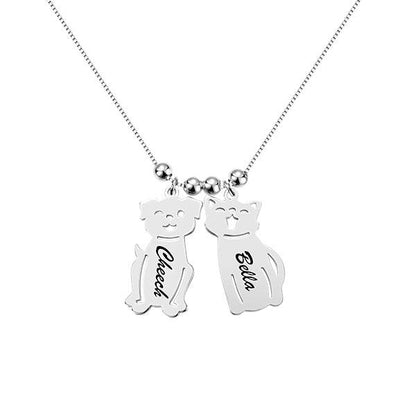 A silver necklace with two pendants shaped like a dog and a cat. The dog pendant is engraved with "Cheech" and the cat pendant with "Bella."
