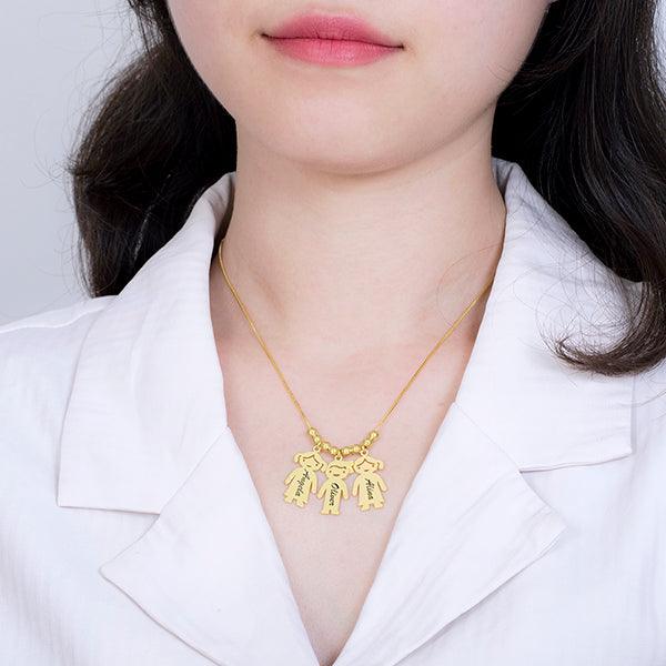 A woman wearing a gold necklace with three pendants shaped like dogs. Each pendant is engraved with different names. She is dressed in a white collared shirt.