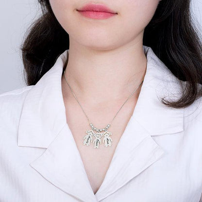 A woman wearing a silver necklace with three pendants shaped like dogs. Each pendant is engraved with different names. She is dressed in a white collared shirt.