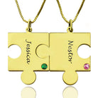 Two interlocking gold puzzle piece necklaces, one labeled "Jessica" with a green gem, and the other labeled "Nestor" with a pink gem.