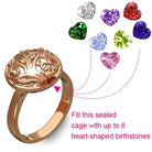 A rose gold ring with a tree of life design, shown with 8 heart-shaped birthstones that can be placed inside the sealed cage. Text: "Fill this sealed cage with up to 8 heart-shaped birthstones."