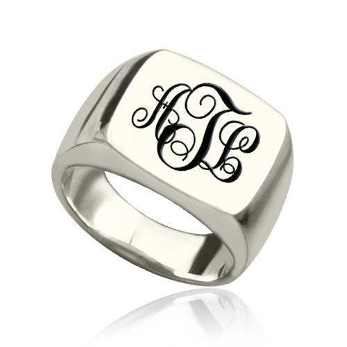 A silver signet ring with a polished rectangular face, featuring the initials "ATL" in an elegant, black cursive monogram style.