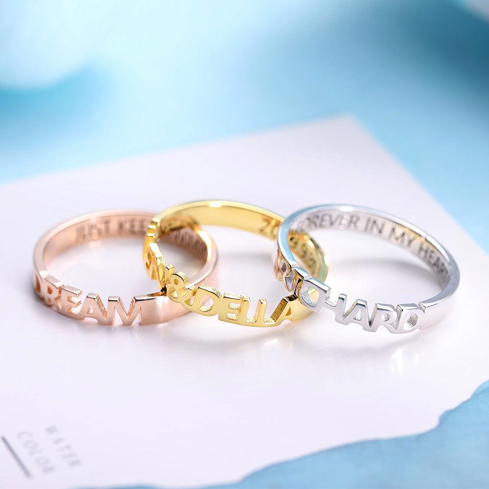 Three rings in silver, rose gold, and gold with cut-out lettering. The silver ring reads "RICHARD FOREVER IN MY HEART," the rose gold ring reads "DREAM JUST KEEP SWIMMING," and the gold ring reads "ALLEN & DELLA 2019.9.30."