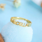 A gold ring with cut-out lettering that reads "ALLEN & DELLA." The inside of the ring is inscribed with the date "2019.9.30."