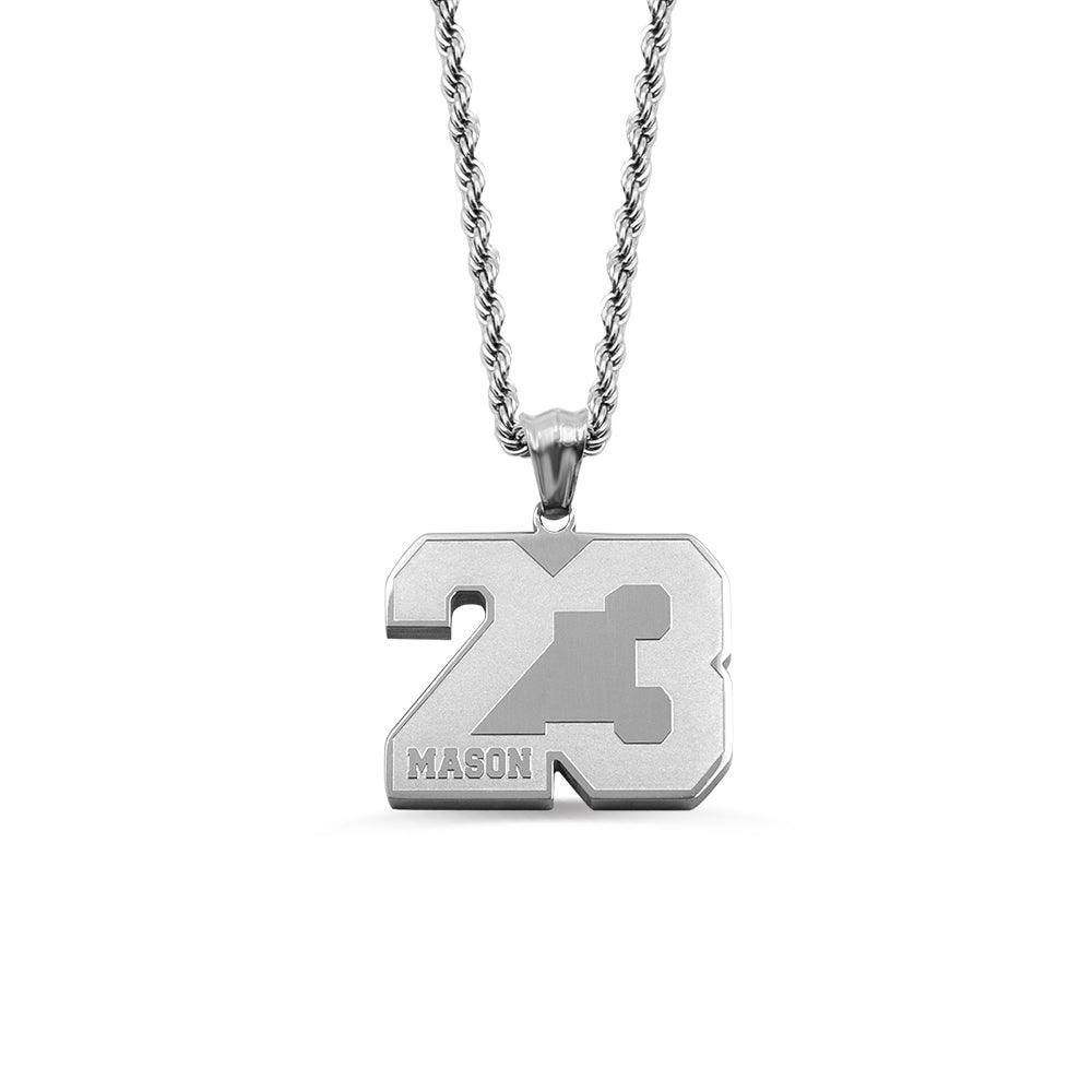 A silver pendant with the number 23 and the name "Mason" engraved on it, hanging from a silver chain, isolated on a white background.