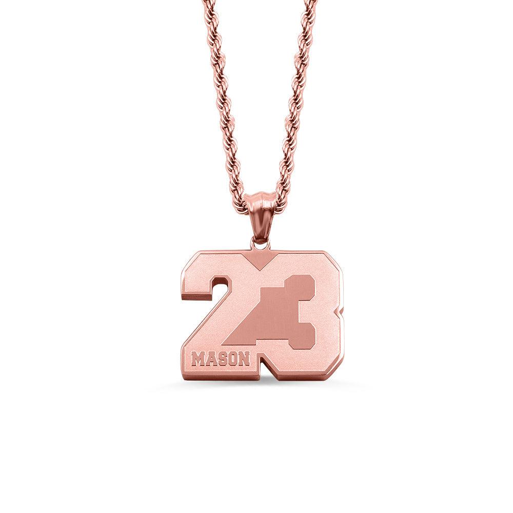 A rose gold pendant with the number 23 and the name "Mason" engraved on it, hanging from a rose gold chain, isolated on a white background.