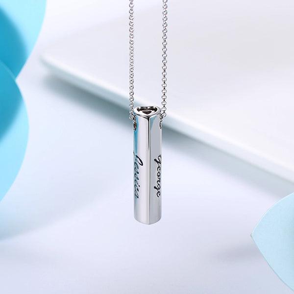 Close-up of a personalized sterling silver bar pendant necklace with "Jessica" and "George" engravings, displayed against a white and blue background.