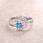 Silver ring with square-cut blue and pink stones, engraved with "Selena" and "Claud" on the sides. The inscription "Our love is eternal" is inside the band.