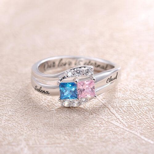 Silver ring with square-cut blue and pink stones, engraved with "Selena" and "Claud" on the sides. The inscription "Our love is eternal" is inside the band.