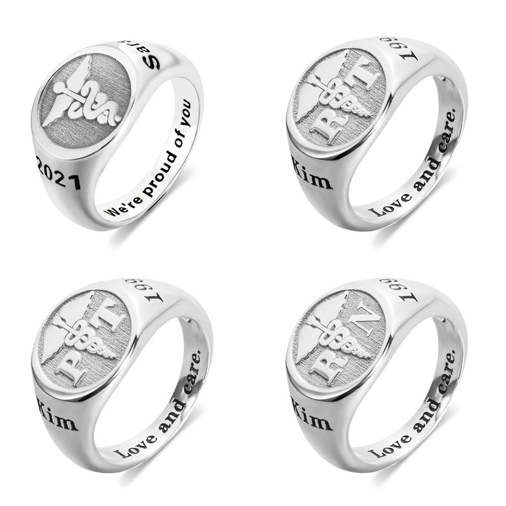 Four silver rings with engraved designs: "RN," a caduceus symbol, "2021," "67," "Kim," and phrases like "We're proud of you" and "Love and care."