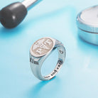 A silver ring with a caduceus symbol and the letters "PT" engraved. The ring also features the name "Kim" and the phrase "Love and care," displayed with medical tools on a blue background.