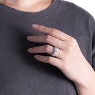 A person wearing a silver custom name ring with the initials 'KR,' showcasing the ring on their finger against a dark shirt.