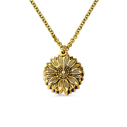 A gold sunflower-shaped locket necklace, closed to display the detailed sunflower design, against a white background.