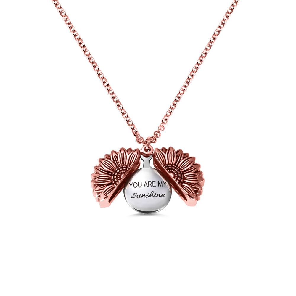 A rose gold sunflower-shaped locket necklace, opened to reveal the message "You Are My Sunshine" engraved inside, displayed against a white background.