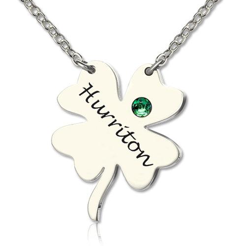 A silver necklace with a four-leaf clover pendant inscribed with the name "Huririton" and a green gemstone embedded in one of the leaves.